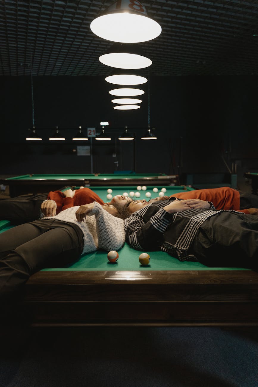 photo of a group of friends lying on a pool table