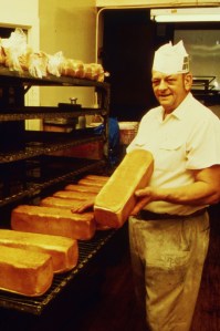 The Misty-Eyed Stormtrooper (Episode II). Photo shows man in white hat and white shirt holding a loaf of bread while he works in a bakery.