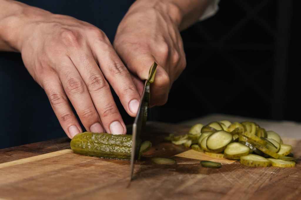 close up photo of a person s hands cutting pickles